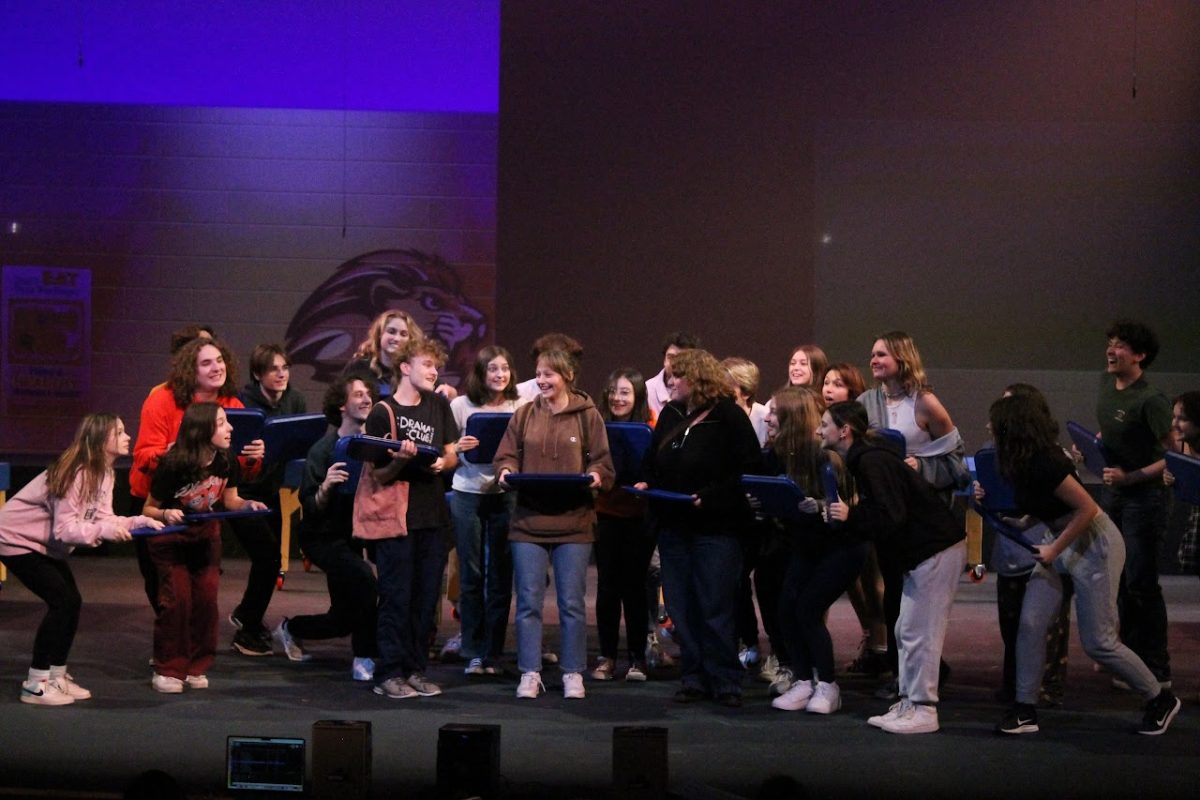 OCHS theatre performers rehearse crowding excitedly around Cady Heron, played by Presley Zarfas, during the song “Where Do You Belong?” for Mean Girls: The Musical, Nov. 6th, 2023.