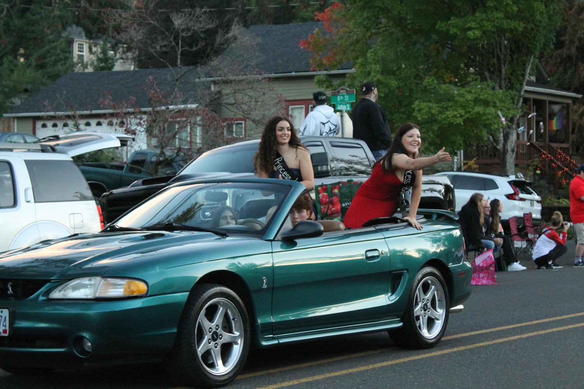 Junior HOCO Court Olivia Behrman and Bailey Larsen throw candy to parade watchers, Oct 20th, 2023.