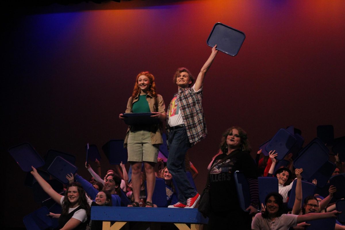 Damian Hubbard played by William Corwin and Cady Heron played by Presley Zarfas stand atop a table as they end the song “Where Do You Belong?” by holding out cafeteria trays in “Mean Girls”, Nov. 16, 2023. Corwin was in the previous show “Shakespeare in Love”, and this was Zarfas’ first show.