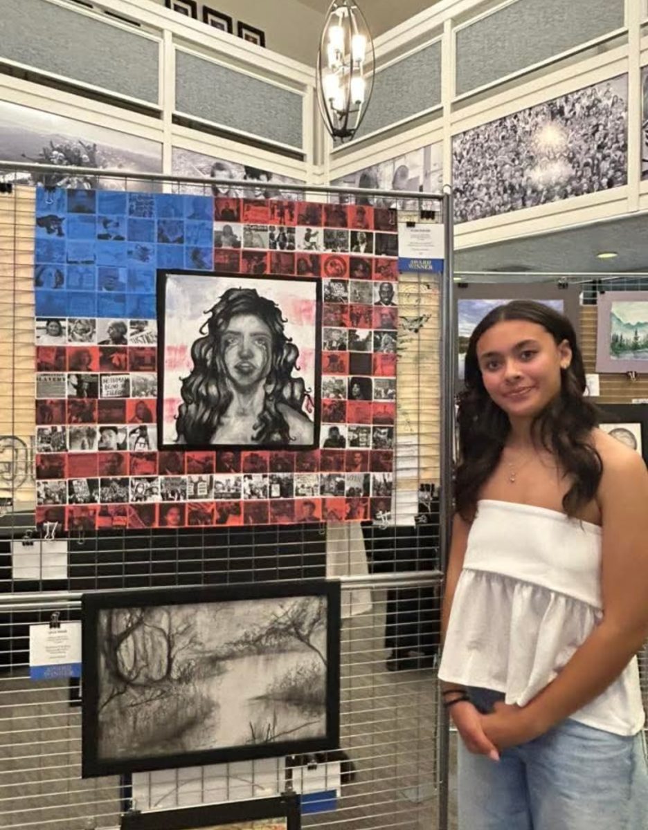 Kylee Turner poses with her award-winning art piece. From her artist statement: "This piece questions why, in a nation that prides itself on freedom, those who don't meet the "American" standards are denied basic rights."